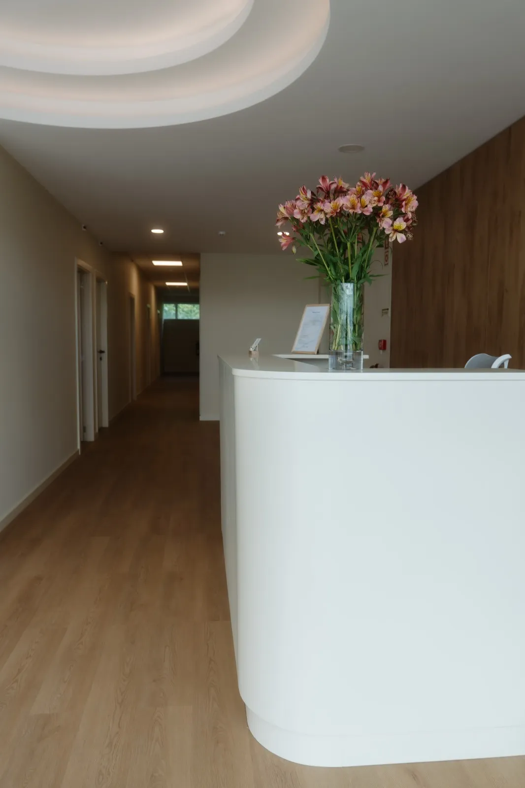 Balcão da receção com flores e, ao fundo, o corredor que leva às salas
