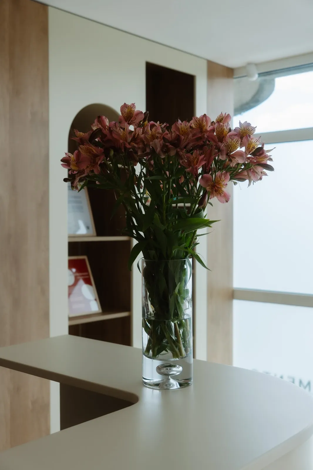 Jarra com flores no balcão da receção, junto a uma janela