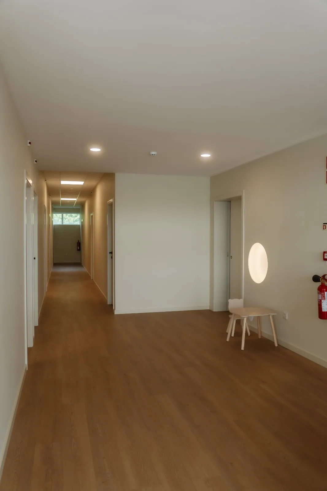 Corredor de acesso às salas de consulta, com chão de madeira e luz suave