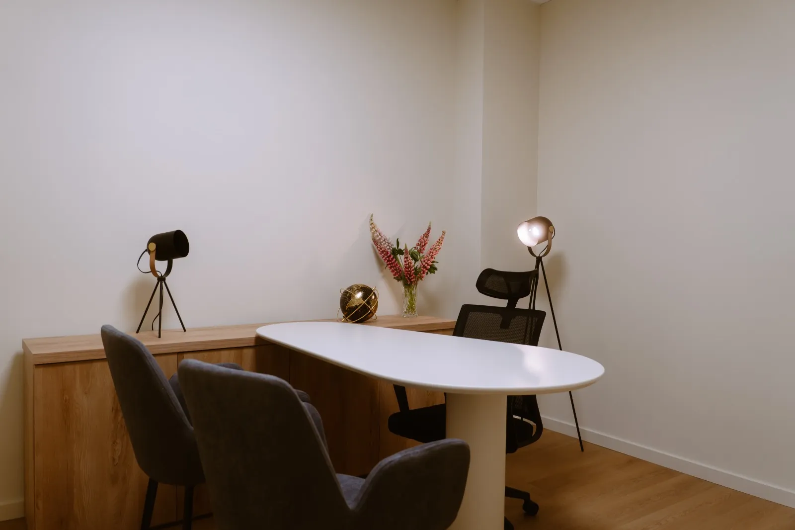 Sala de consulta com candeeiros de pé e arranjo de flores sobre o móvel